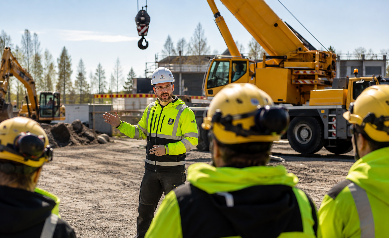 Työntekijöitä osallistumassa kone- ja nostotöiden turvallisuuskoulutukseen teollisuusympäristössä.